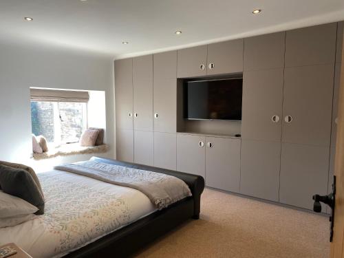 een slaapkamer met een bed en een flatscreen-tv bij Honeysuckle Cottage in Oughtibridge
