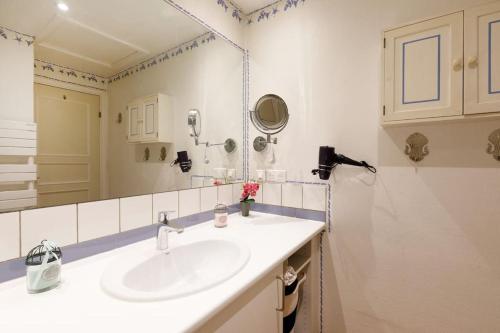 een witte badkamer met een wastafel en een spiegel bij Super Manoir à Cannes YourHostHelper in Cannes