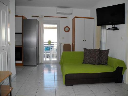 - un canapé vert dans le salon doté d'une télévision dans l'établissement Vassilikos Apartment, à Flogita