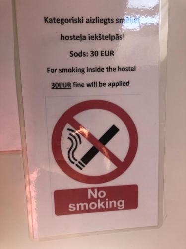 un cartello sulla porta con un cartello di divieto di fumo di AivisApartment a Riga