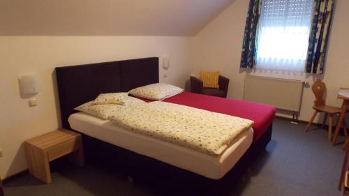 a bedroom with a large bed with a red bedspread at Gasthaus Pension Rezatgrund in Windsbach