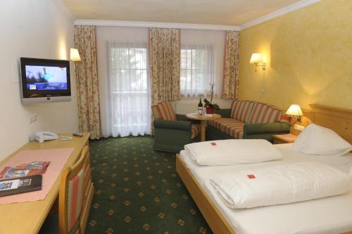 マウテルンドルフにあるHotel Stegmühlhofのベッドとリビングルームが備わるホテルルームです。