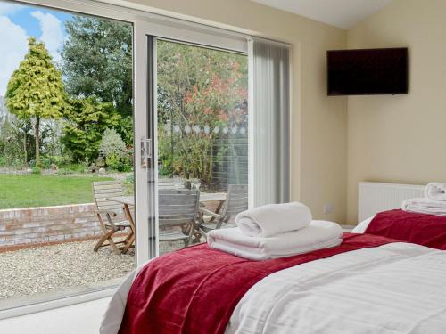 a bedroom with two beds and a sliding glass door at End Cottage in Tibthorpe