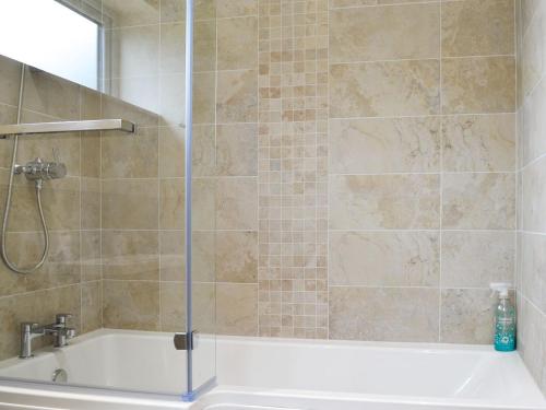 a bathroom with a shower and a bath tub at End Cottage in Tibthorpe