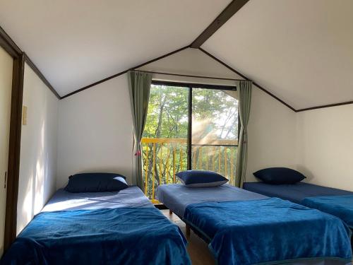 three beds in a room with a window at 秩父 思源屋 