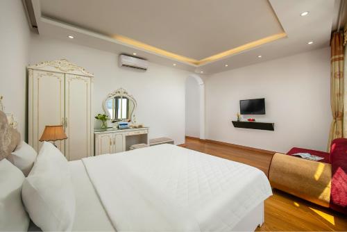 a bedroom with a large white bed and a tv at Hanoi Kingly Hotel in Hanoi