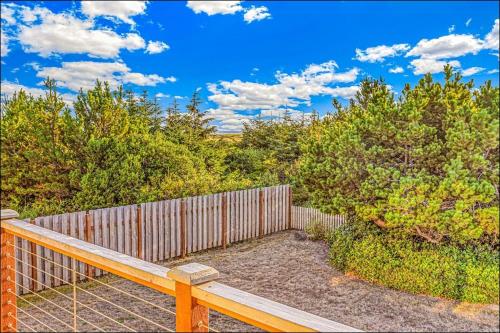 a wooden deck with a fence and trees at Brathouse By The Sea in Copalis Beach