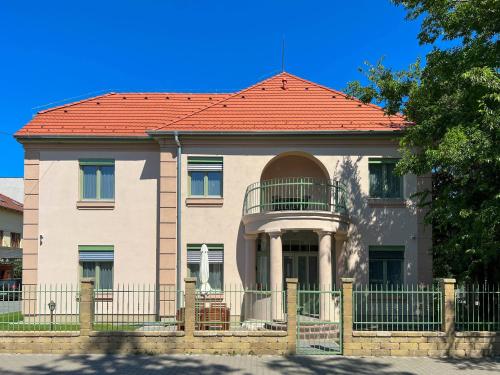 ein Haus mit rotem Dach und einem Zaun in der Unterkunft Lujza Apartman in Fonyód