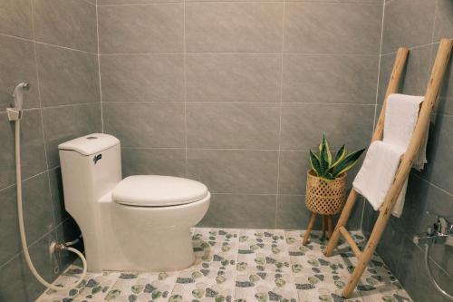 baño con aseo y planta en Phòng Mơ - Nhà Mơ Homestay Bến Tre, en Ben Tre