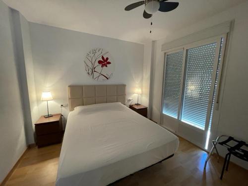 1 Schlafzimmer mit einem weißen Bett und 2 Fenstern in der Unterkunft Apartment with terrace in Ardales