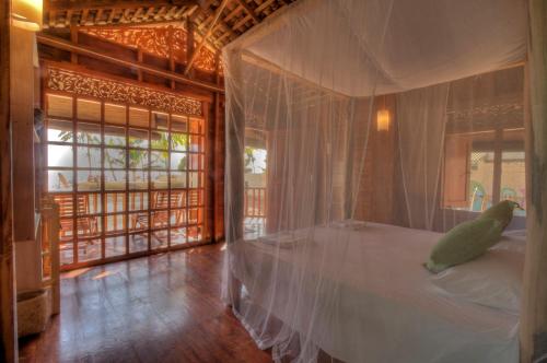 um quarto com uma cama de dossel e um pássaro sentado nela em The Green Rooms Surf & Yoga Camp - ON THE BEACH - Prime location Weligama Bay em Weligama