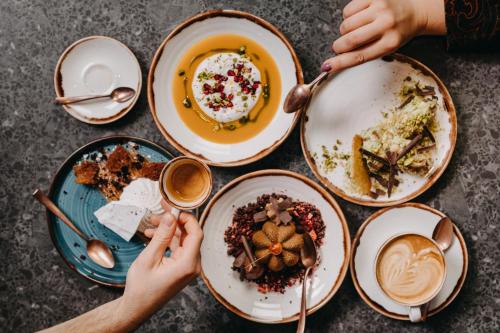 a table full of plates of food with people eating at OREA Place Seno in Prague