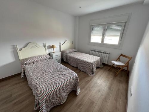 雷東德拉的住宿－Apartamento vacacional，一间卧室设有两张床、一把椅子和一个窗户。