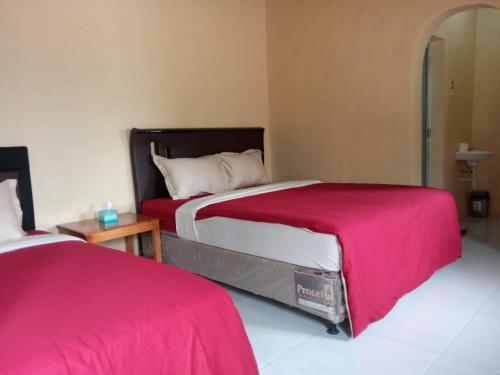 1 dormitorio con 2 camas con sábanas rojas y mesa en Tube Bromo Homestay en Probolinggo