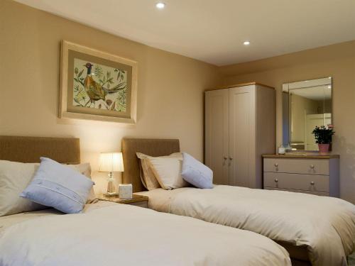 a bedroom with two beds and a mirror at The Lodge Cottage in Keilour