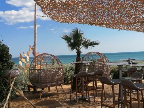 een tafel en stoelen met de oceaan op de achtergrond bij La Cage Village Naturiste in Cap d'Agde