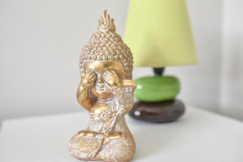 une petite statue d'or sur une table à côté d'une lampe dans l'établissement La Mésange Enchantée, à Grospierres