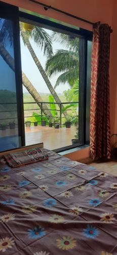 a bedroom with a large window with a view of the ocean at Bageecha B&B- Vaayu in Alibaug