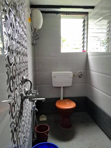 a small bathroom with a toilet and a window at Bageecha B&B- Vaayu in Alibaug