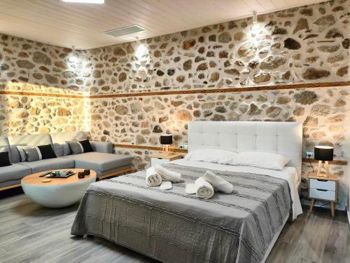 a bedroom with a large bed and a stone wall at Dream Nest Meteora in Kalabaka