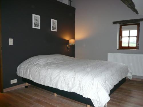 a bedroom with a white bed with a black wall at Gite des Comagnes in Limbourg