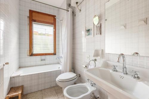 a white bathroom with a toilet and a tub and a sink at Can Sebrià in Gélida