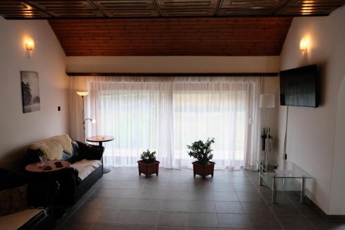 a living room with a couch and a large window at Alea Apartmanok in Harkány