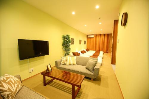 a living room with couches and a flat screen tv at PrimeRoom別府 浜脇温泉前 in Beppu