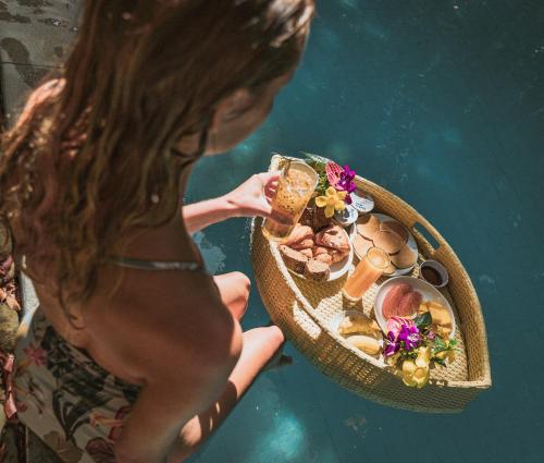een vrouw in het water met een bord eten in haar handen bij Valley Village Phu Quoc in Phu Quoc