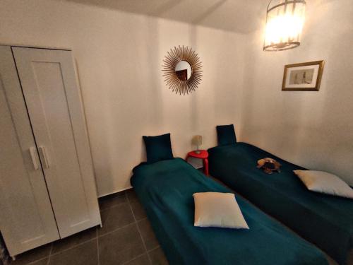 a bedroom with two green beds and a mirror at Alea Apartmanok in Harkány