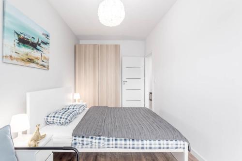 a white bedroom with a bed and a chair at Enjoy! Ursus in Warsaw
