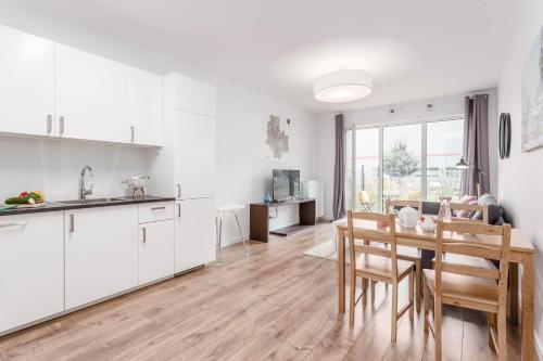 a kitchen and dining room with white cabinets and a table at Enjoy! Ursus in Warsaw