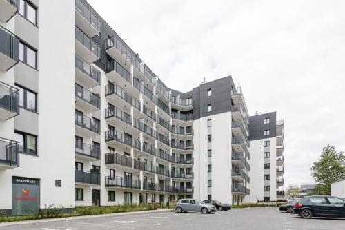 an apartment building with balconies and cars parked in a parking lot at Enjoy! Ursus in Warsaw