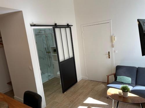 - un salon avec un canapé bleu et une porte en verre dans l'établissement Le Studio Cosy, à Orléans