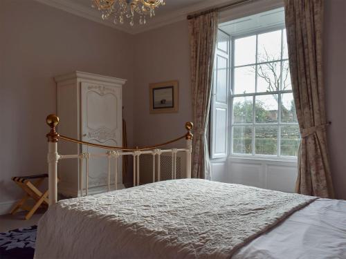 a bedroom with a bed with a chandelier and a window at Sneaton Hall Whitby in Sneaton