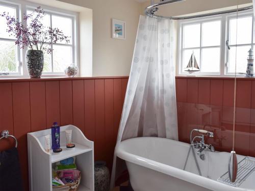 a bathroom with a tub and a shower curtain at Sneaton Hall Whitby in Sneaton