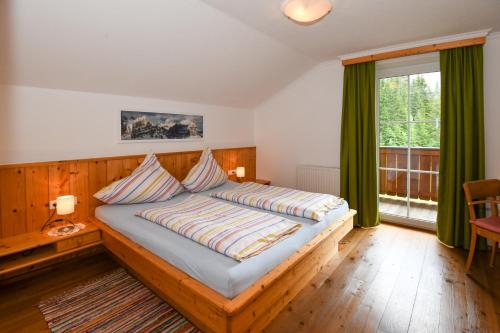 1 dormitorio con cama de madera y cortinas verdes en Strickhof, en Schladming