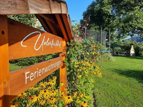 a wooden sign in a garden with yellow flowers at Unterfrickhof in Owingen