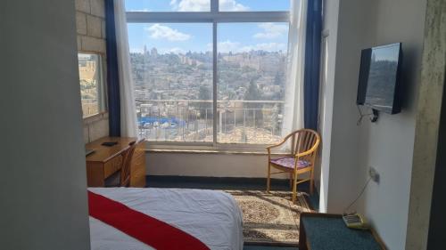 a bedroom with a view of a city from a window at Jerusalem Panorama Hotel in Jerusalem