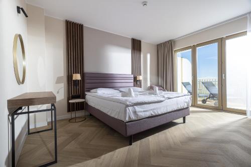 a bedroom with a large bed and a balcony at Hotel Meridian in Chałupy