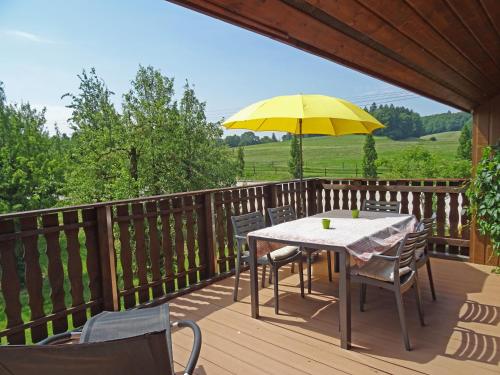 a table and chairs with a yellow umbrella on a deck at Guesthouse La Moliere, 3 bedrooms, private house, horse farm, full nature in Murist