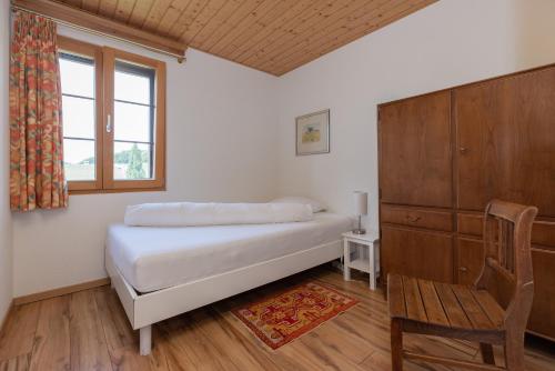um quarto com uma cama, uma cadeira e uma janela em Guesthouse La Moliere em Murist