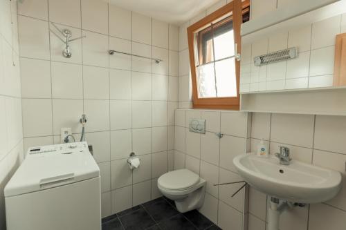 a white bathroom with a toilet and a sink at Guesthouse La Moliere in Murist