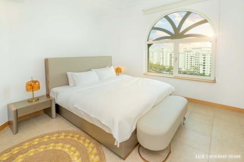 a bedroom with a large white bed and a window at LUX - The Shoreline Penthouse Suite in Dubai