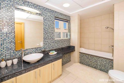 ein Badezimmer mit einem Waschbecken, einer Badewanne und einem WC in der Unterkunft LUX - The Shoreline Penthouse Suite in Dubai