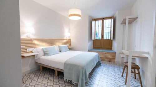a bedroom with a bed and a desk and a window at Veranera Hostel in Estepona