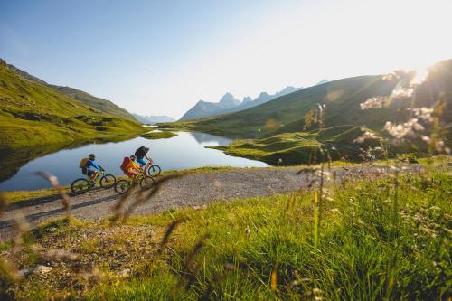 two people riding bikes on a trail next to a lake at Aparthotel Spitzer in Sankt Gallenkirch