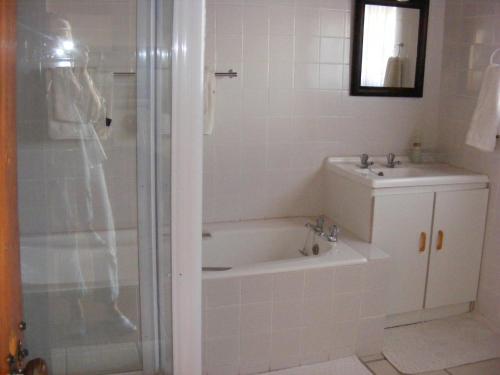 a bathroom with a tub and a sink and a shower at Pepper Tree Accommodation in Beaufort West