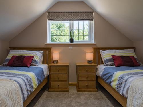 a attic bedroom with two beds and a window at Spilstead Barn in Sedlescombe