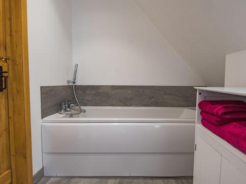 a bathroom with a white tub and a red towel at Spilstead Barn in Sedlescombe